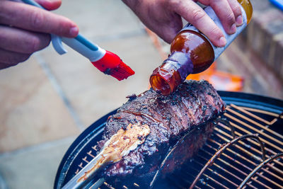 Close-up of person preparing food on barbecue grill