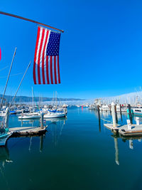 Sailboats moored on sea against blue sky