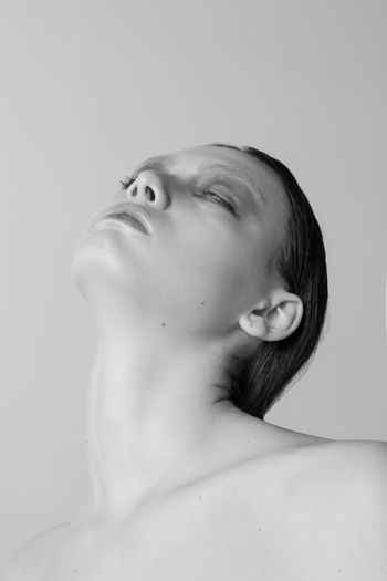 CLOSE-UP PORTRAIT OF YOUNG WOMAN AGAINST WALL