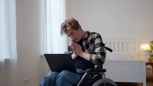 Young man with hands clasped talking on video conference