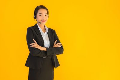 Portrait of a smiling young woman against yellow background