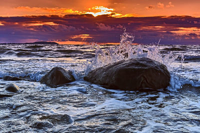 Aerial view of rocks in sea against sky during sunset