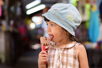 Close-up of girl eating ice cream cone while standing outdoors