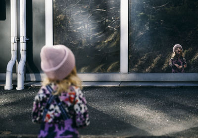 Girl reflecting in building wall