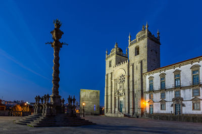 Low angle view of statues on building against blue sky