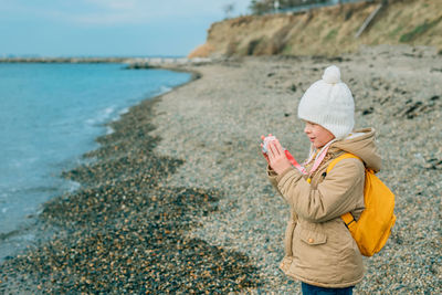 Rear view of woman standing at beach