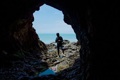 Man holding camera while standing in cave at beach
