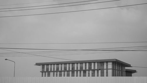 Low angle view of built structure and cables against sky