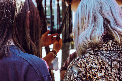 Rear view of women buying clothes in street market 