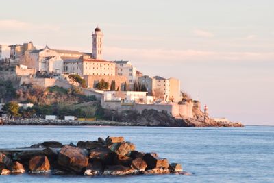 Buildings by sea against sky