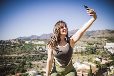 Side view of young woman standing against sky