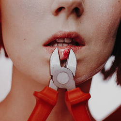 Midsection of woman cutting lips with pliers