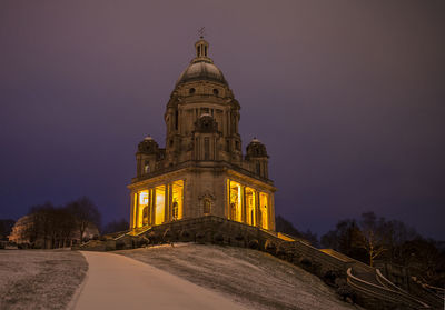 Low angle view of illuminated cathedral against cloudy sky at dusk