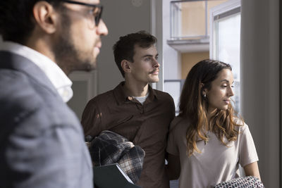 Multiracial couple looking away during meeting with male real estate agent at home