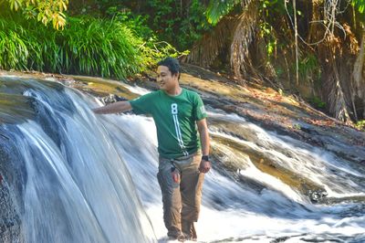 Man standing by waterfall
