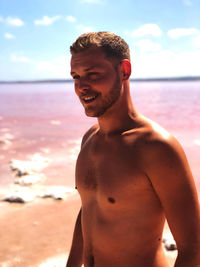 Young man smiling while standing on a red beach