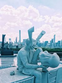 Statue in city against cloudy sky