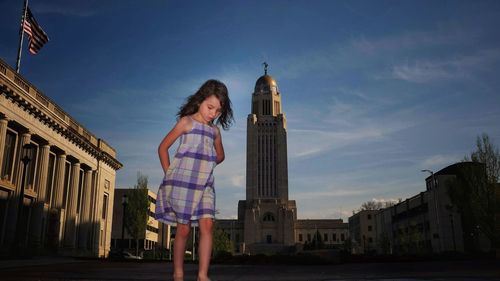 Girl standing against nebraska state capitol building 