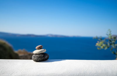 Close-up shot of pebbles stacked on each other in a balance with santorini caldera in the background