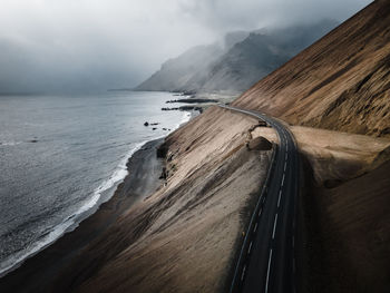 Scenic view of road by sea against sky