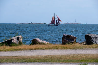 Sailboat sailing in sea against clear sky