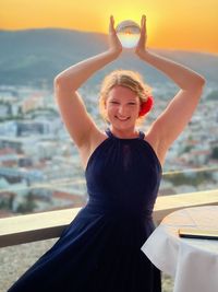 Portrait of young woman standing by railing
