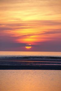 Scenic view of sea against dramatic sky during sunset