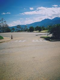 Scenic view of road by mountains against sky