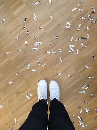 Low section of person standing by confetti on hardwood floor