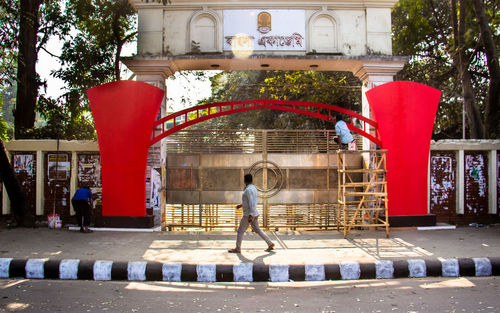 People standing by red building in city