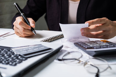 Midsection of man holding paper with text on table