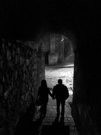 Silhouette couple walking in tunnel