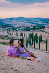 Friends sitting on land against sky