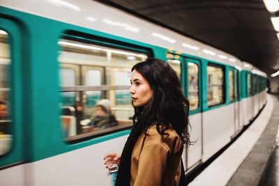 Young woman looking at train at railroad station