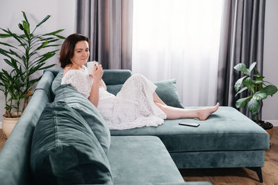 Portrait of woman sitting on sofa at home