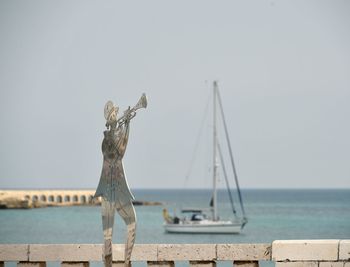 View of statue by sea against clear sky