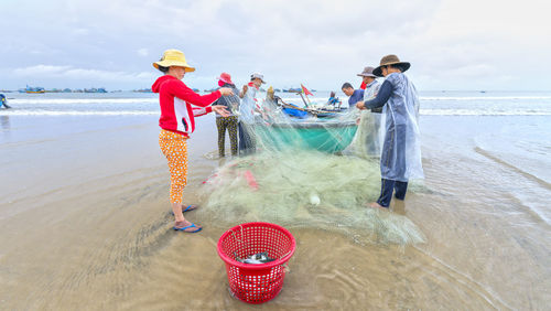 People standing at beach against sky