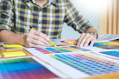 Midsection of man drawing on color swatches at office