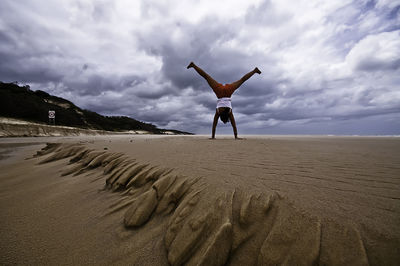 Scenic view of beach against cloudy sky