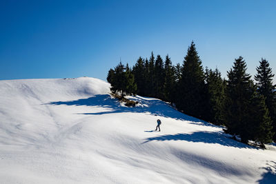 Person skiing on snowcapped mountain against sky during winter