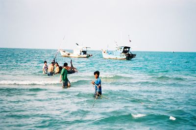 People fishing in sea against clear sky