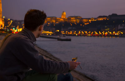 Man sitting on riverbank at night