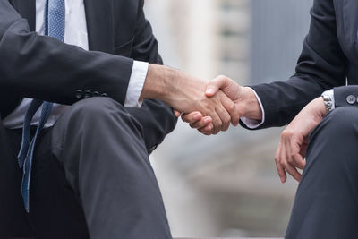 Midsection of business people shaking hands