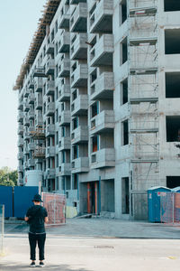 Rear view of man standing on street against buildings