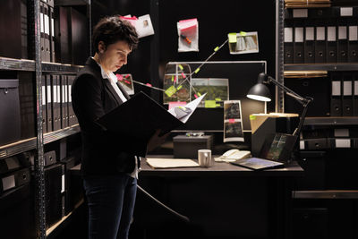 Young man using laptop while standing in library