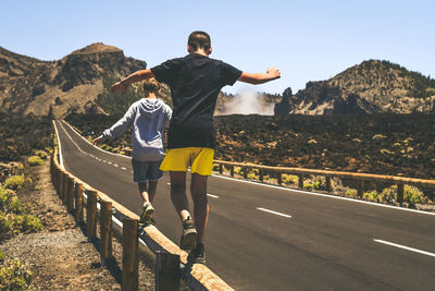 Rear view of man standing on road against mountain