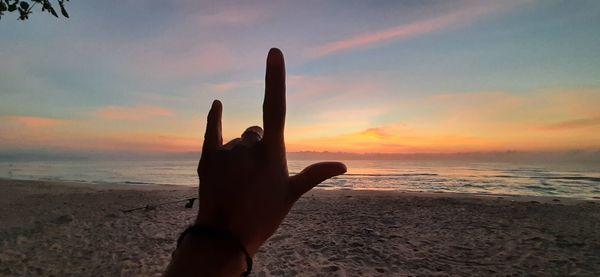 Person hand on beach during sunset