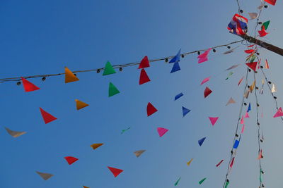 Low angle view of bunting hanging against clear blue sky