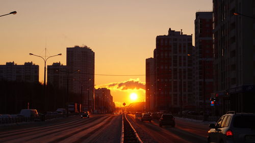 City street and buildings against sky during sunset