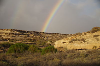 Scenic view of rainbow over mountain against sky